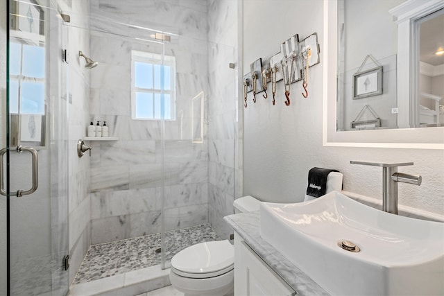 bathroom featuring vanity, toilet, a textured wall, and a stall shower