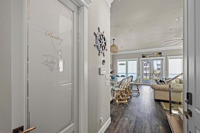 hallway featuring visible vents, dark wood finished floors, recessed lighting, ornamental molding, and a textured wall