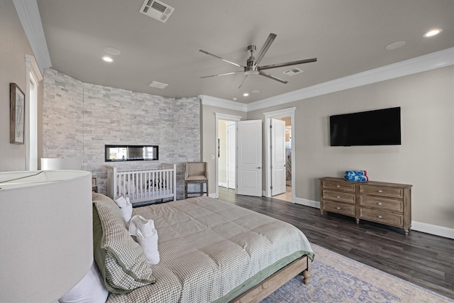 bedroom with visible vents, wood finished floors, baseboards, and ornamental molding