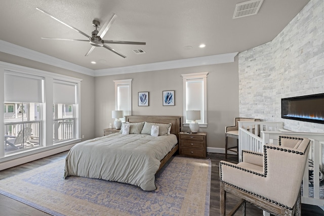 bedroom with visible vents, wood finished floors, ornamental molding, and a fireplace