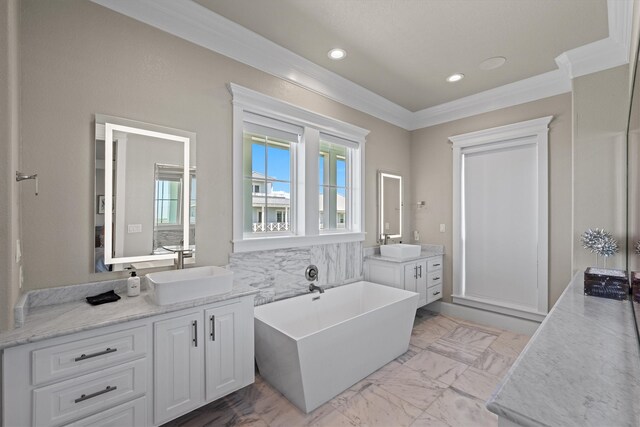 full bath with marble finish floor, a freestanding tub, ornamental molding, and a sink