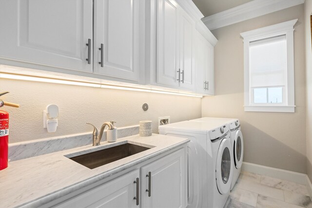 washroom featuring washing machine and clothes dryer, crown molding, baseboards, cabinet space, and a sink