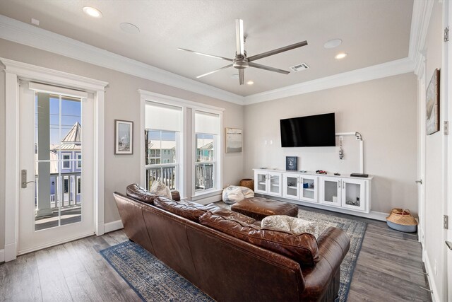 living room featuring a ceiling fan, visible vents, a wealth of natural light, and ornamental molding