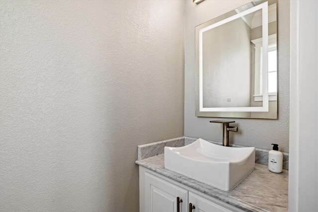 bathroom featuring vanity and a textured wall