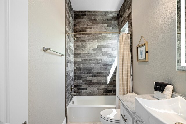 bathroom featuring a textured wall, toilet, vanity, and shower / bath combination with curtain