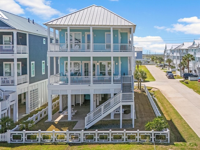 back of property featuring stairway, fence, a standing seam roof, covered porch, and metal roof