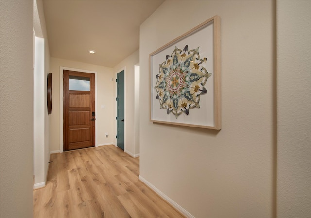 hall featuring light wood-type flooring and baseboards