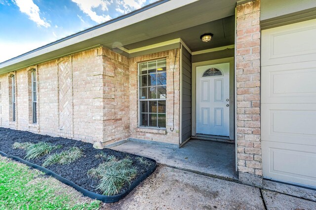 entrance to property with brick siding and an attached garage