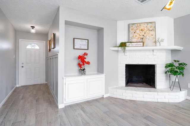 interior space with a fireplace, a textured ceiling, baseboards, and wood finished floors