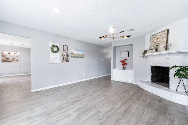 unfurnished living room featuring baseboards, visible vents, wood tiled floor, a fireplace, and a textured ceiling