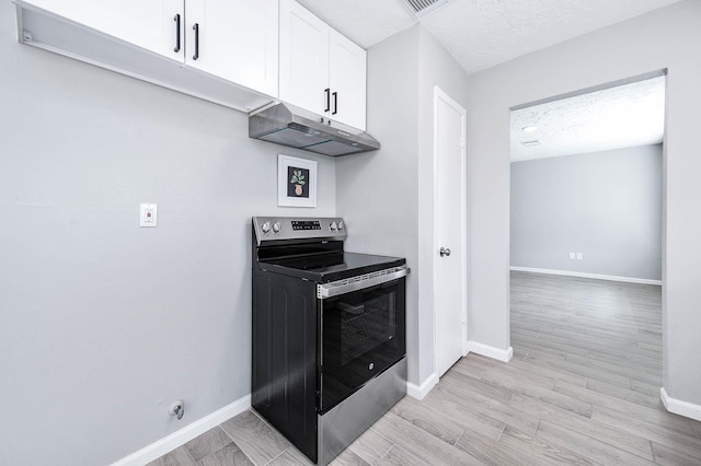 kitchen with under cabinet range hood, white cabinets, stainless steel range with electric stovetop, and baseboards