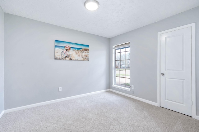 empty room featuring baseboards, a textured ceiling, and carpet flooring