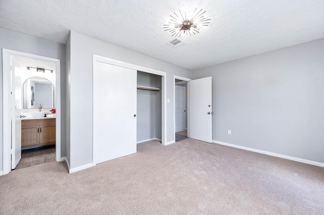 unfurnished bedroom with baseboards, visible vents, a closet, a textured ceiling, and light colored carpet