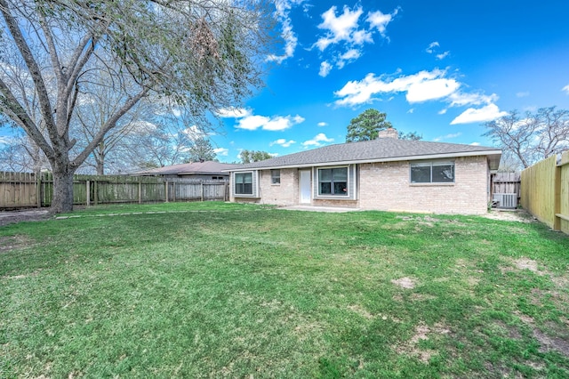 back of property with brick siding, a lawn, a chimney, and a fenced backyard