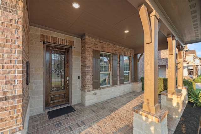 entrance to property with covered porch and brick siding