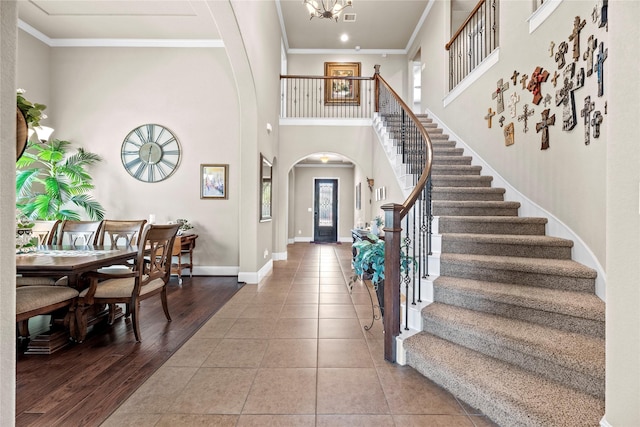 foyer entrance with stairs, baseboards, arched walkways, and ornamental molding