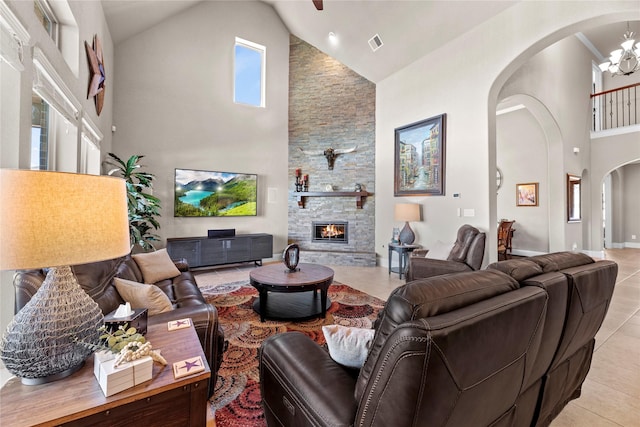 living area with visible vents, arched walkways, a fireplace, light tile patterned floors, and a towering ceiling