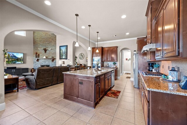 kitchen with arched walkways, appliances with stainless steel finishes, light stone countertops, and a sink