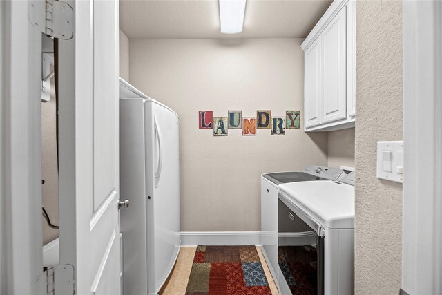 clothes washing area with cabinet space, independent washer and dryer, and baseboards