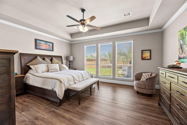 bedroom featuring visible vents, a raised ceiling, dark wood-style floors, and a ceiling fan