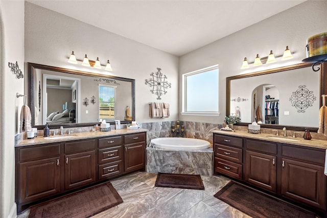 full bath featuring two vanities, a bath, and a sink