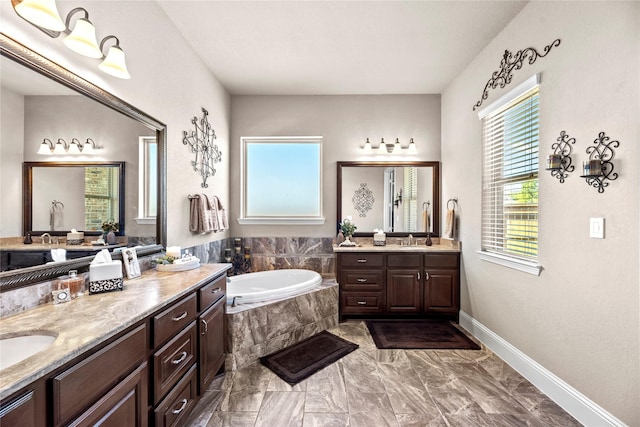 full bath with a sink, baseboards, two vanities, and a bath