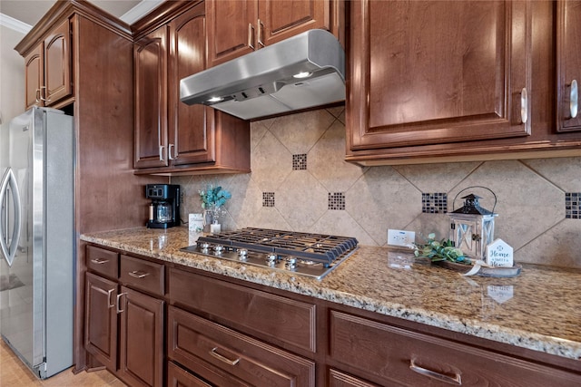 kitchen with under cabinet range hood, backsplash, appliances with stainless steel finishes, and light stone counters