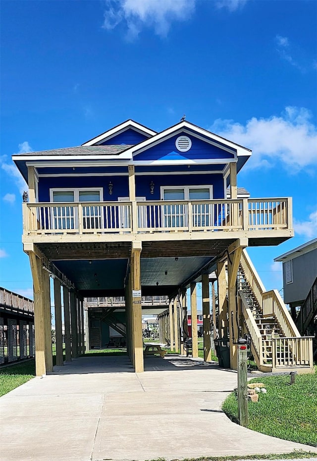 beach home with a carport, driveway, and stairs