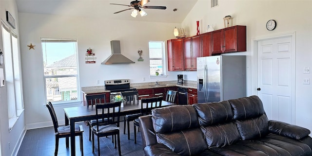 kitchen featuring a sink, open floor plan, reddish brown cabinets, appliances with stainless steel finishes, and wall chimney range hood