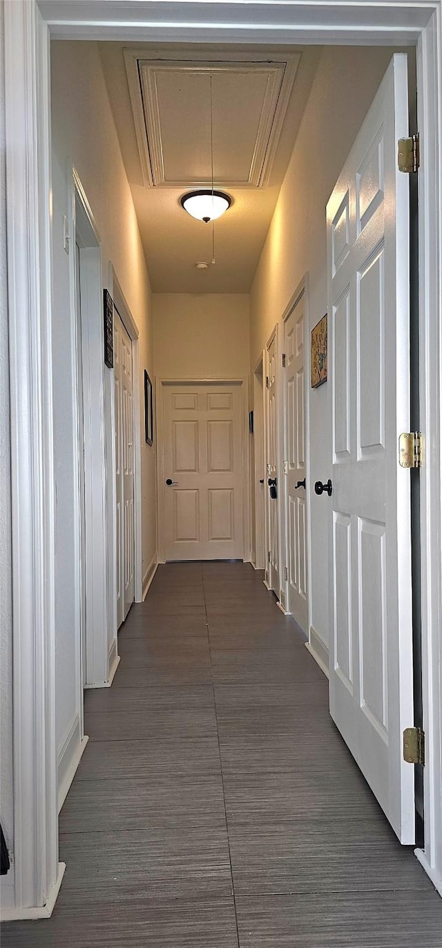 corridor featuring attic access and dark wood finished floors