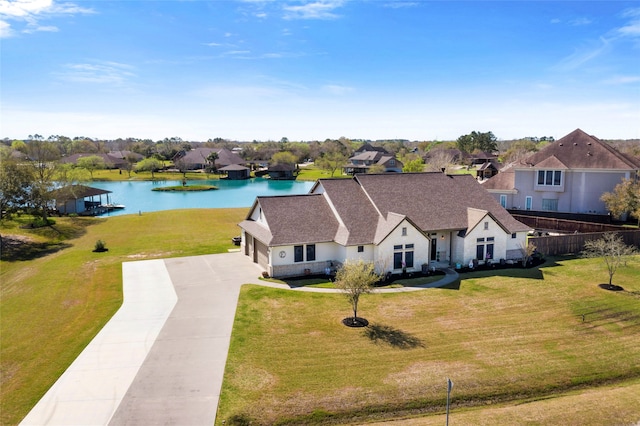 view of front of property with a water view, driveway, fence, roof with shingles, and a front yard