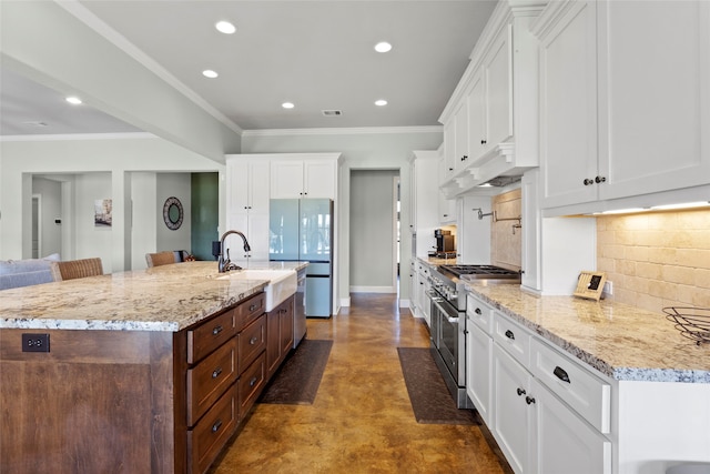 kitchen with a sink, high end stainless steel range oven, finished concrete flooring, white cabinetry, and freestanding refrigerator