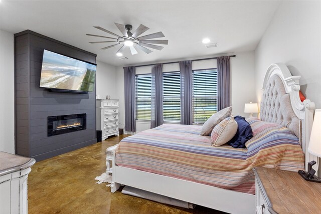 bedroom featuring finished concrete floors, a fireplace, and a ceiling fan