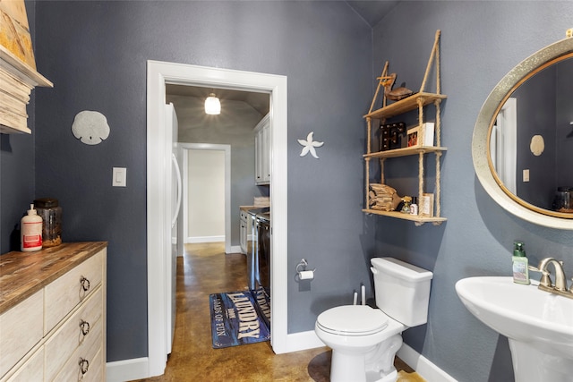 bathroom featuring washer / dryer, toilet, baseboards, and a sink