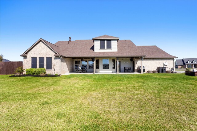 back of house featuring a patio, a yard, fence, and brick siding