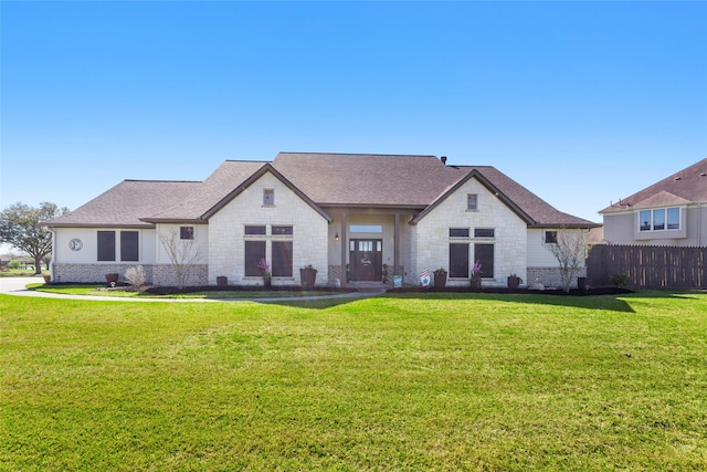 back of property featuring a yard, brick siding, a shingled roof, and fence