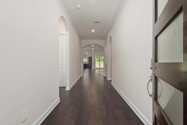 hall featuring dark wood finished floors, crown molding, arched walkways, and visible vents