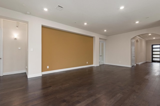 unfurnished room featuring visible vents, baseboards, recessed lighting, arched walkways, and dark wood-type flooring