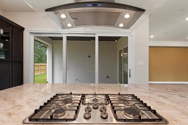 interior space featuring dark brown cabinets, light stone countertops, stainless steel gas cooktop, range hood, and recessed lighting