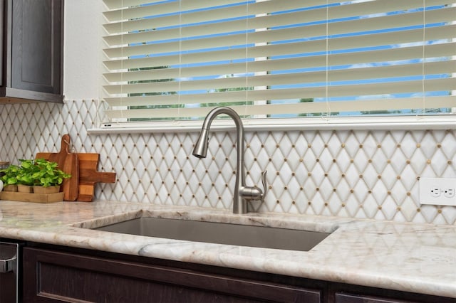 details with dark brown cabinetry, light stone countertops, tasteful backsplash, and a sink