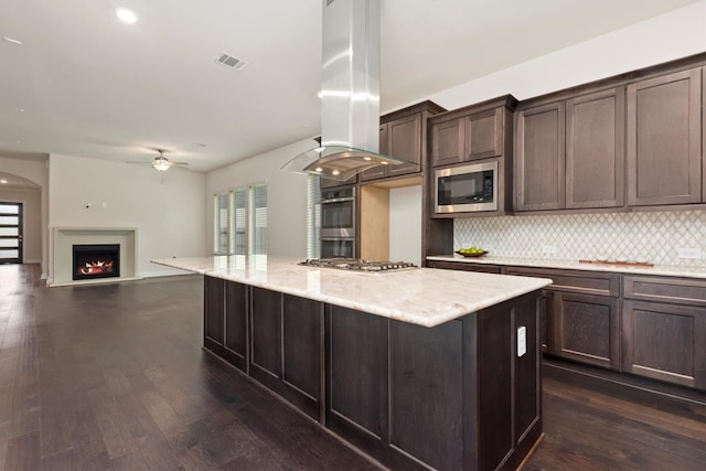 kitchen with stainless steel appliances, plenty of natural light, dark brown cabinets, and island range hood