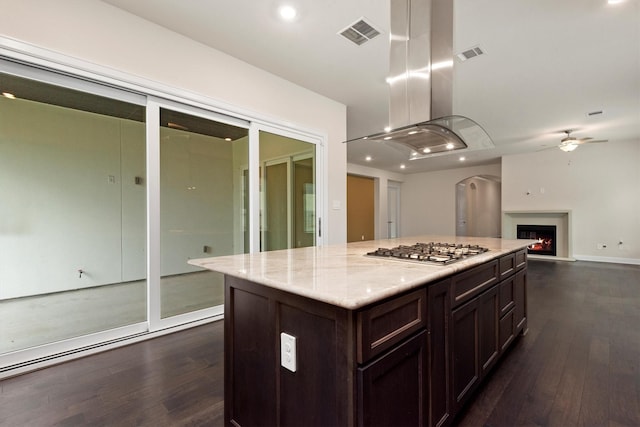 kitchen featuring stainless steel gas stovetop, visible vents, dark wood-style flooring, and a lit fireplace