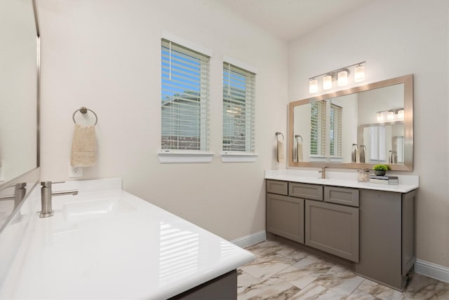 full bathroom featuring a sink, baseboards, two vanities, and marble finish floor