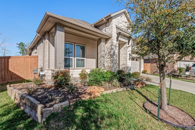 view of front facade with fence, concrete driveway, a front yard, a garage, and stone siding