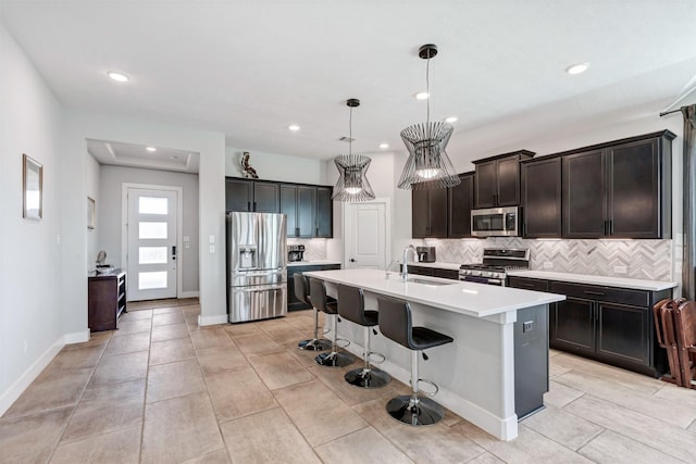 kitchen featuring tasteful backsplash, light countertops, a kitchen breakfast bar, stainless steel appliances, and a sink