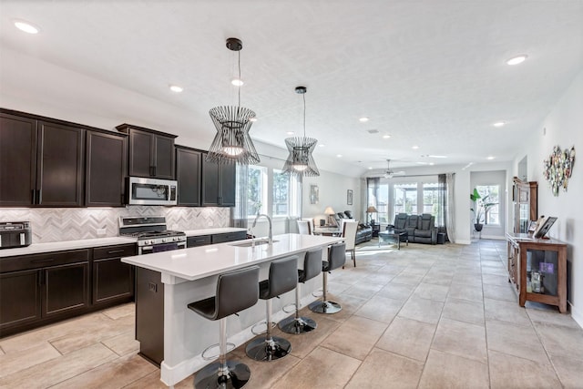 kitchen featuring a sink, light countertops, appliances with stainless steel finishes, tasteful backsplash, and open floor plan