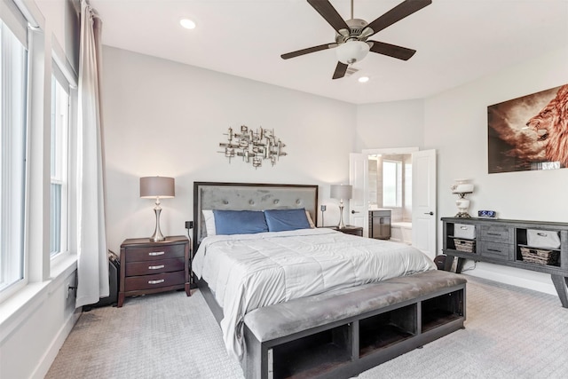 bedroom featuring recessed lighting, baseboards, light colored carpet, and ensuite bath