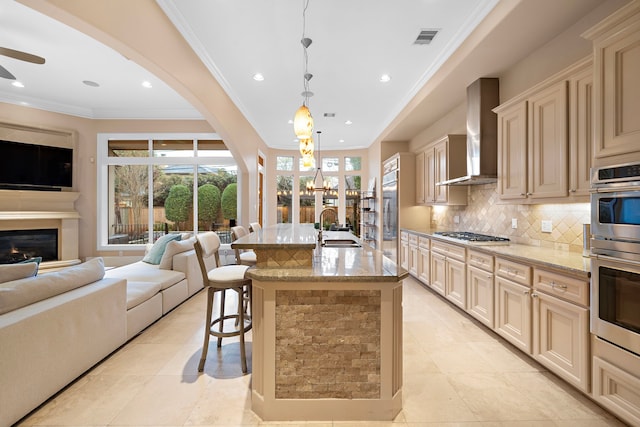 kitchen with cream cabinets, wall chimney exhaust hood, visible vents, and open floor plan