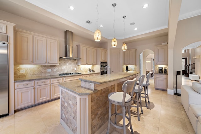 kitchen featuring arched walkways, visible vents, stainless steel appliances, and wall chimney exhaust hood