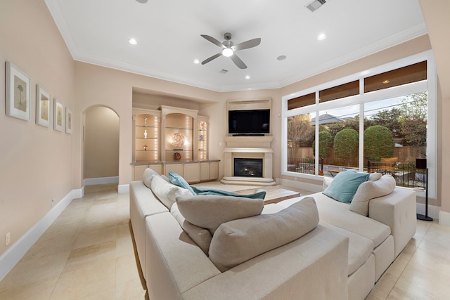 living area with baseboards, arched walkways, a glass covered fireplace, and ornamental molding